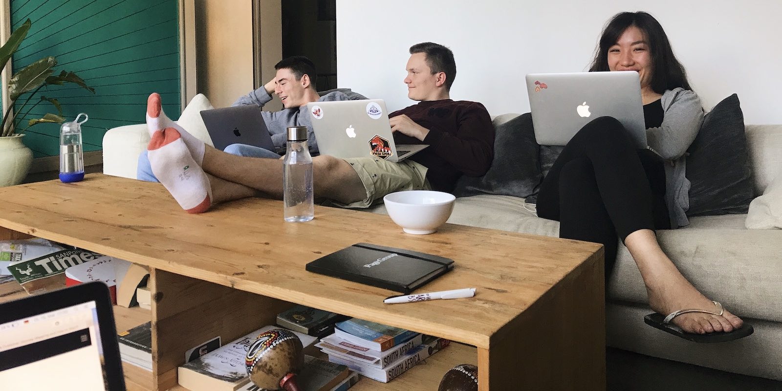 Interns relaxing at the sofa with their pc and smiling for the camera