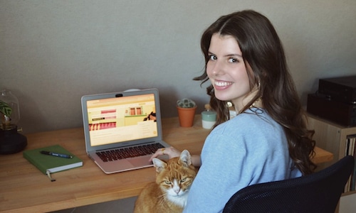intern sitting holding her cat with her laptop on the table