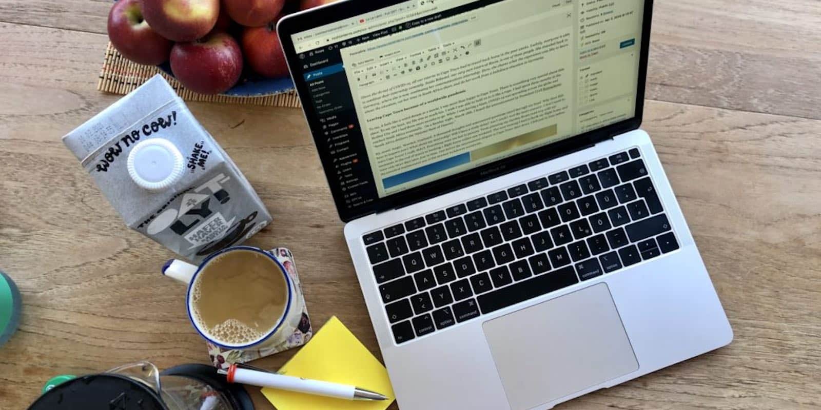 flat lay photo of laptop, food, notepad and a pen