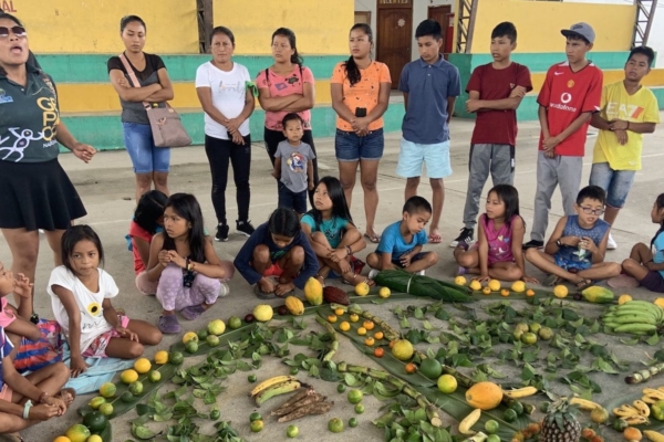 volunteers and local children forming a circle with different fruits