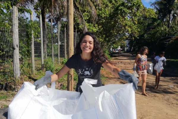 woman smiling while holding a big garbage bag