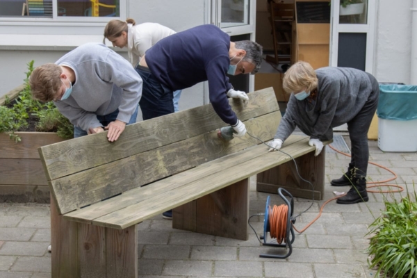 Volunteers sanding and painting a bench