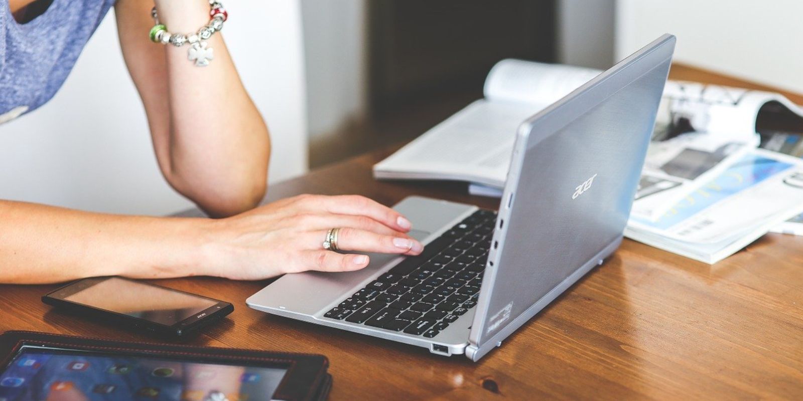 a woman using a laptop on a wooden table