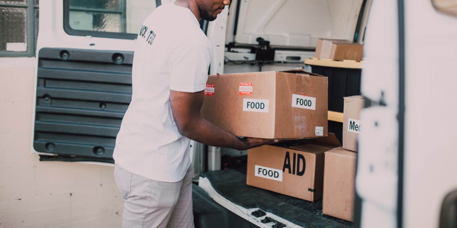 a volunteer putting donation boxes at the back of a van