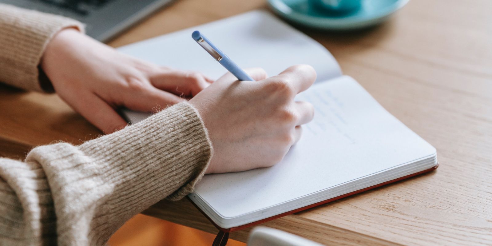 a person writing in a notebook with a pen