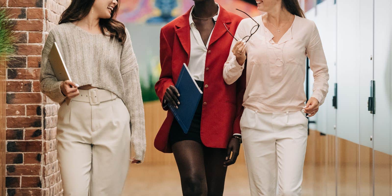 Diverse successful businesswomen smiling and walking together in modern workplace