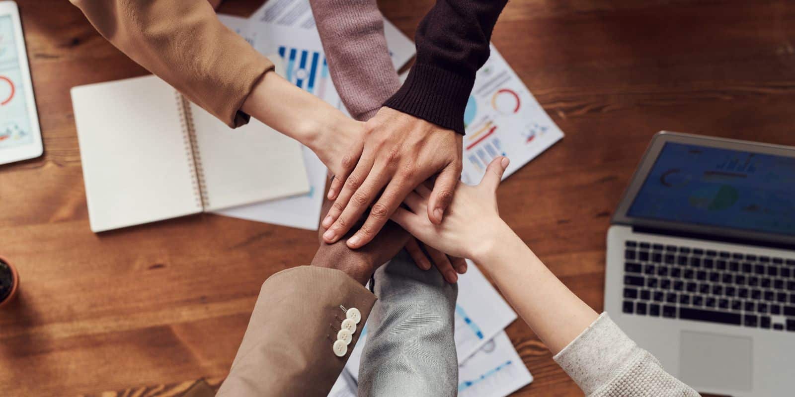 a group of business people putting their hands together on a table