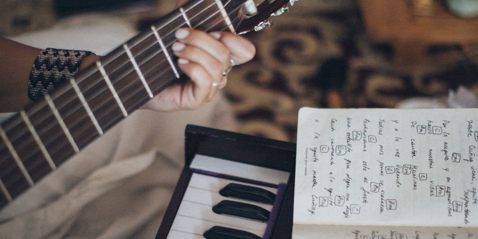 a hand holding the guitar handle and a music book on top of a piano
