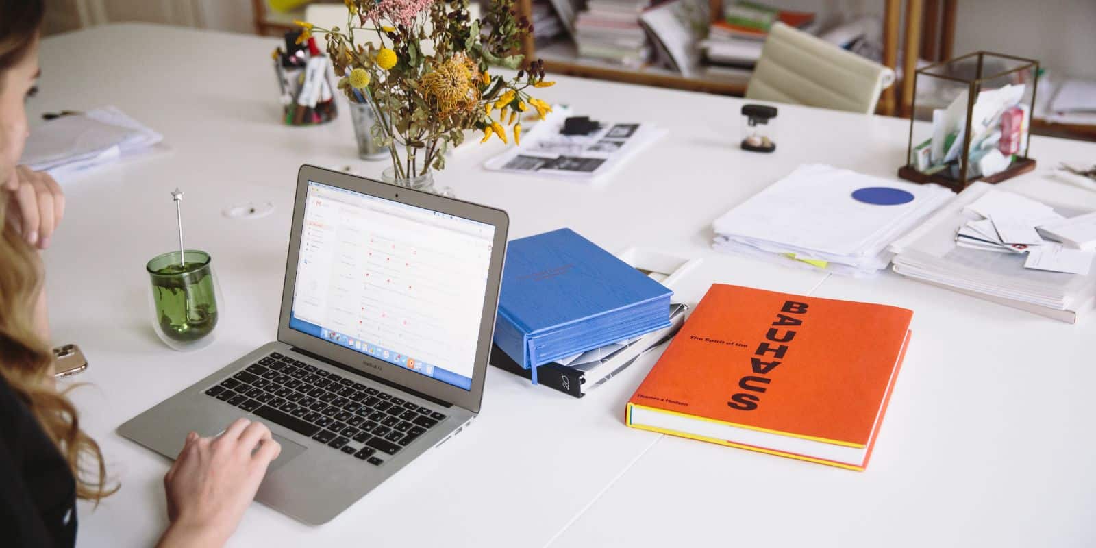 woman using her laptop with books and papers on the table