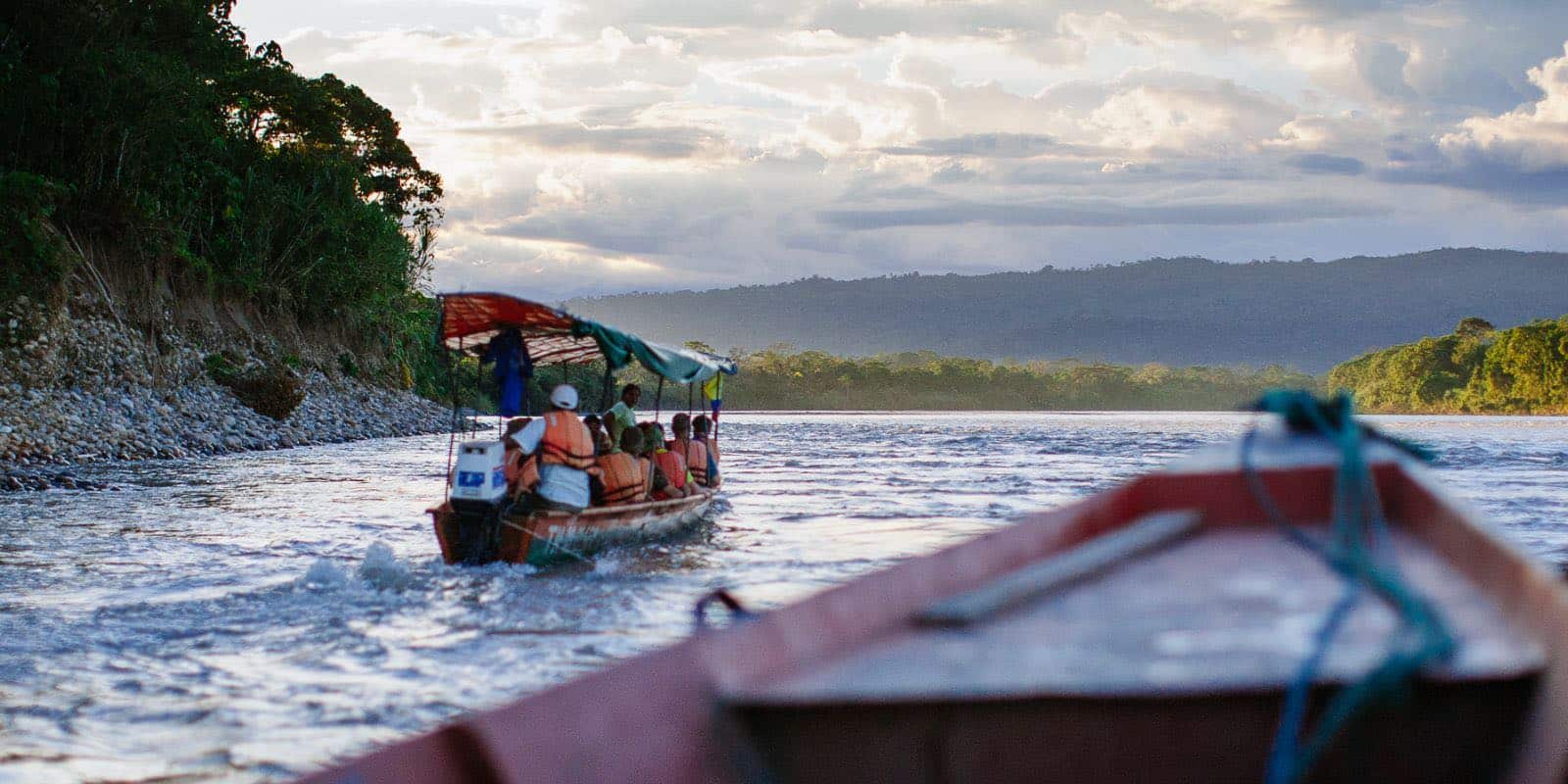 people riding a boat on a river in Tena, Napo, Ecuador