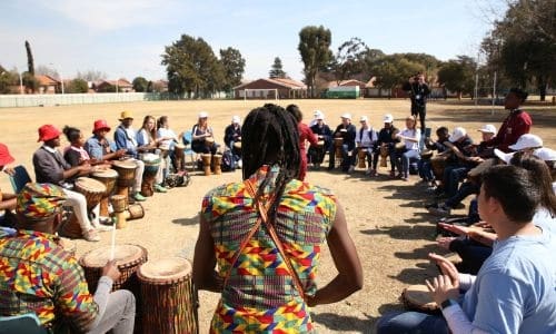 a group of volunteers and locals gather in a circle outdoors