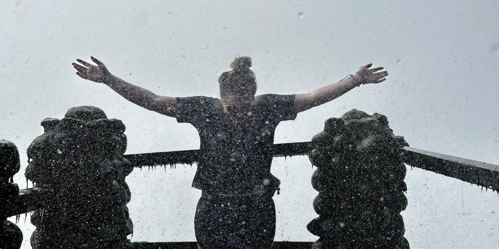 volunteer lifting her hands and enjoying the pouring rain