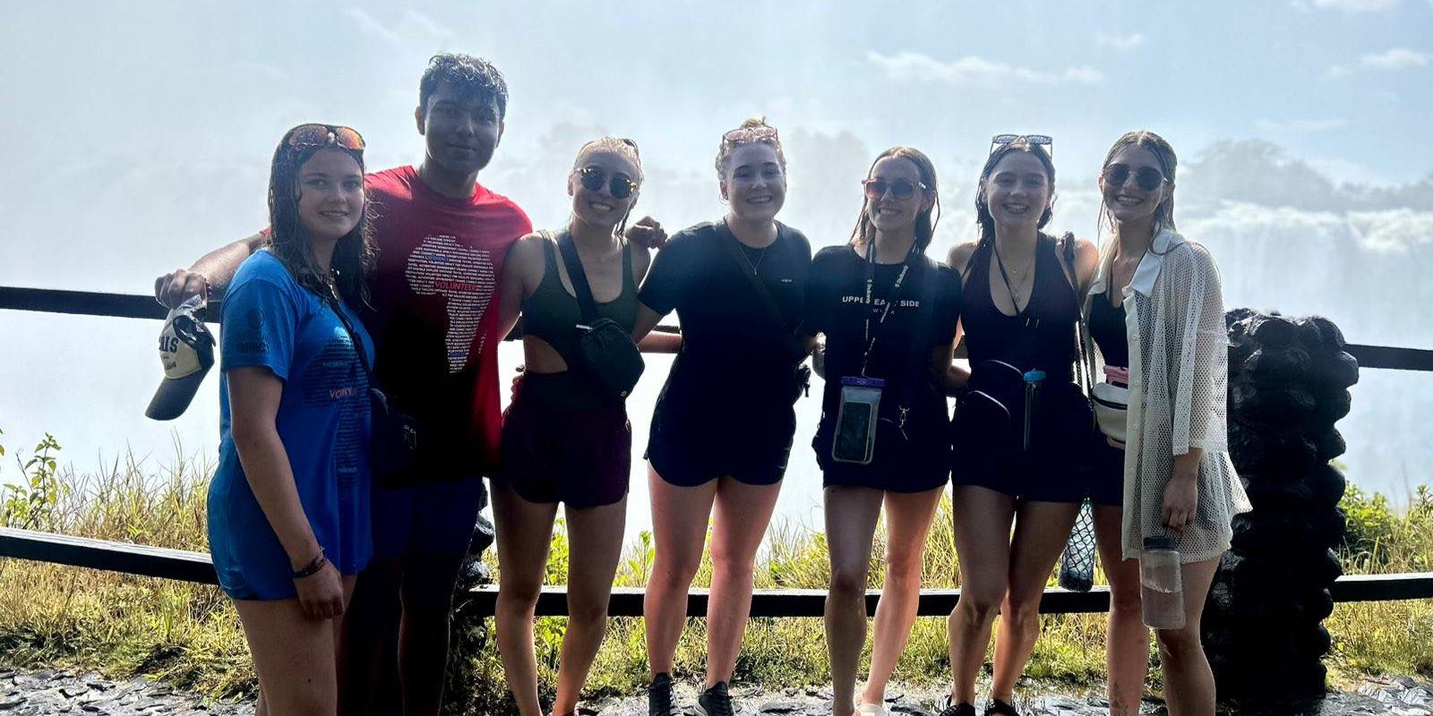 a group of people posing in front of a waterfall