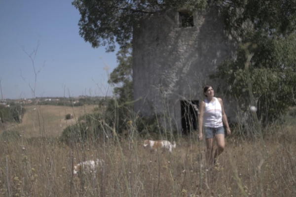 Girl walking in field with a tree