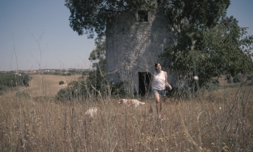 Girl walking in field with a tree