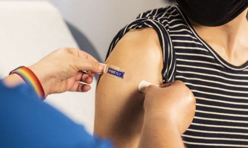 health care provider places a bandage on the injection site of a patient