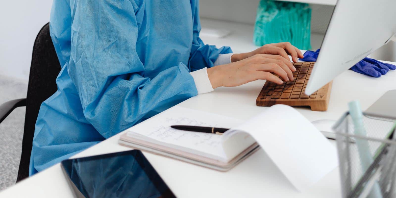 a medical intern in her scrubs typing on her keyboard