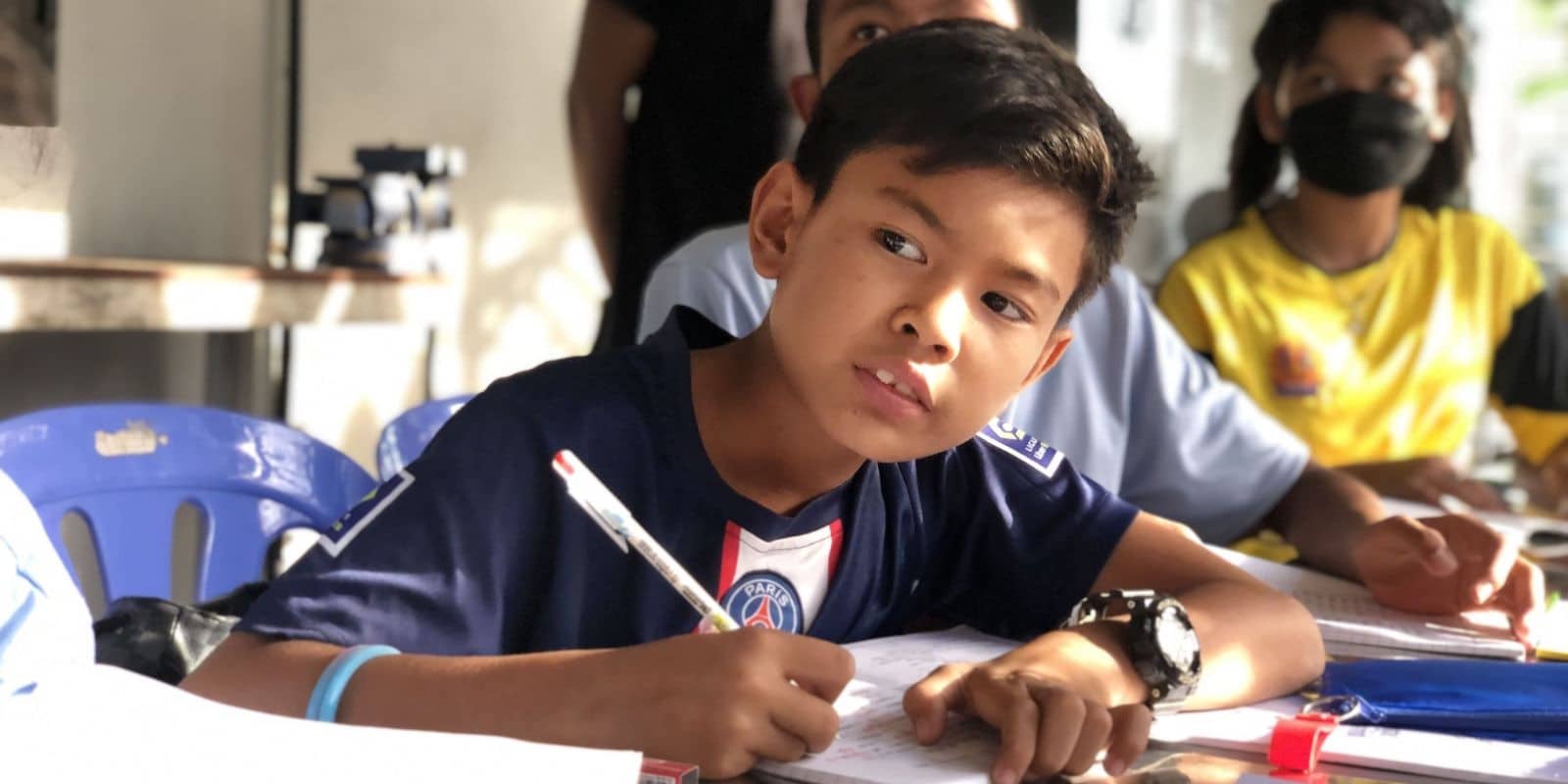A boy is sitting at a desk with a pen and paper