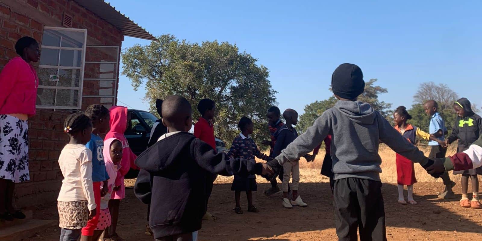 children in Zambia holding each other and forming a circle outdoor