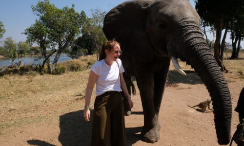 a woman standing next to an elephant