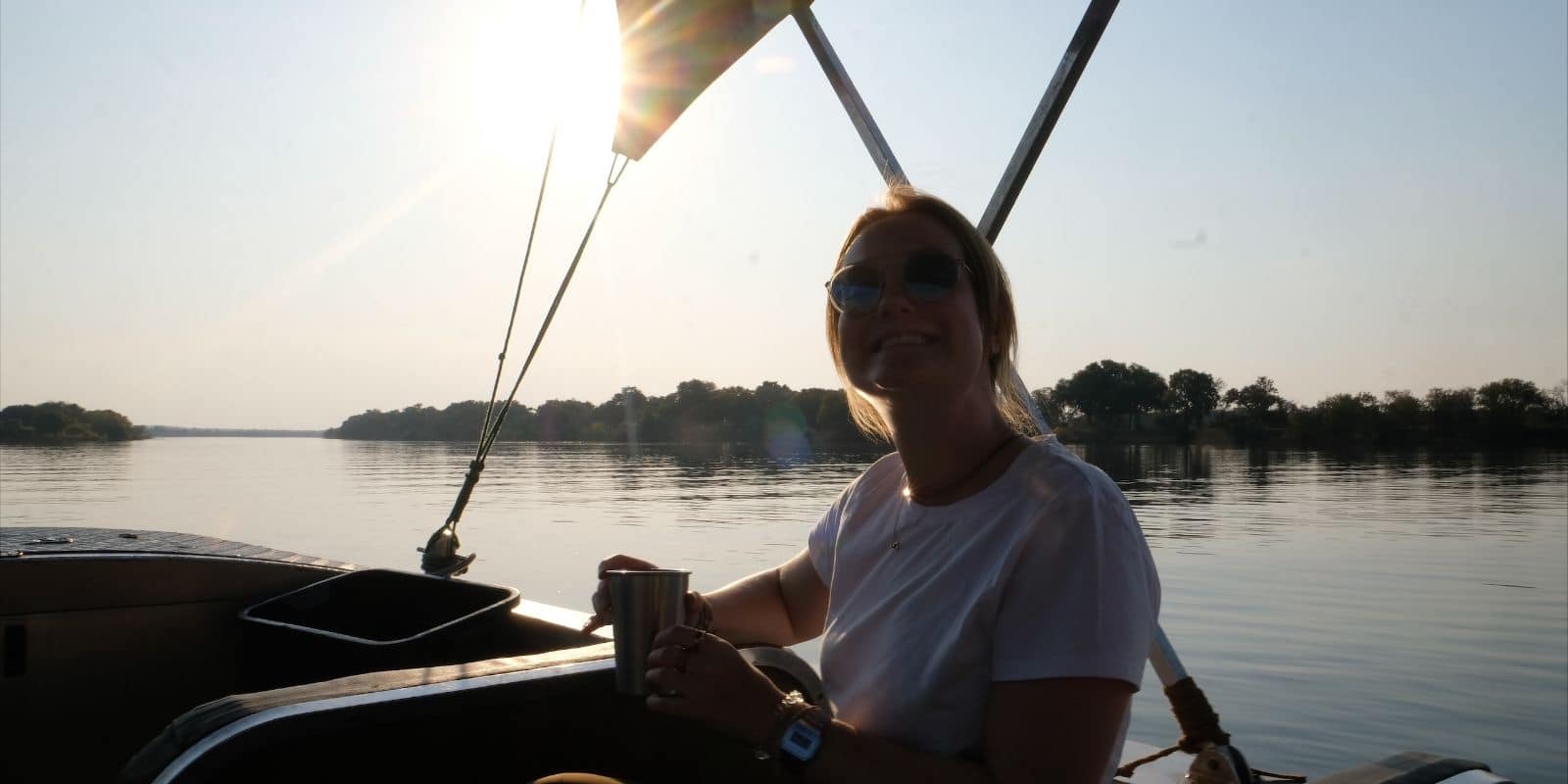 A woman sitting in the back of a boat with a cup of coffee