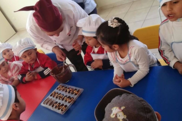 A group of children sitting at a table with hats on.