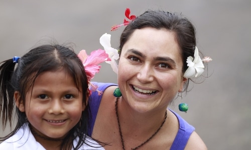 A woman smiles while holding a young girl in Ecuador