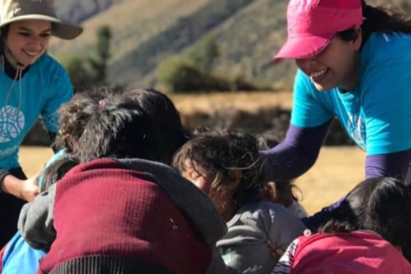 A group of women in blue shirts helping a group of children