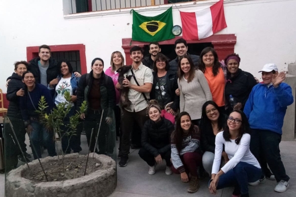 A group of people posing in front of a house with Brazilian flags