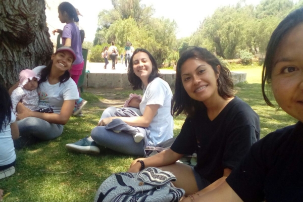 A group of girls sitting on the ground in front of a tree