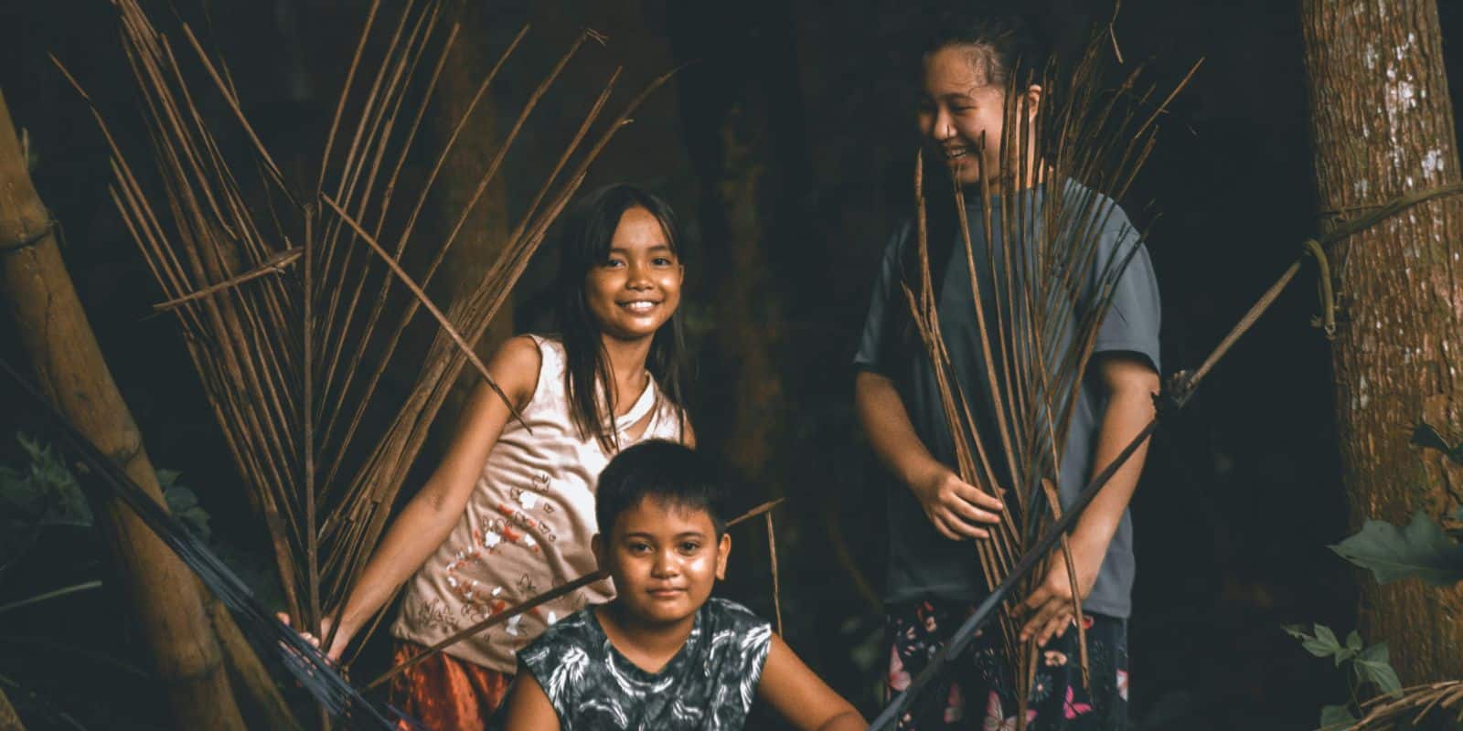 a woman in gray shirt standing beside the two kids near the hammock