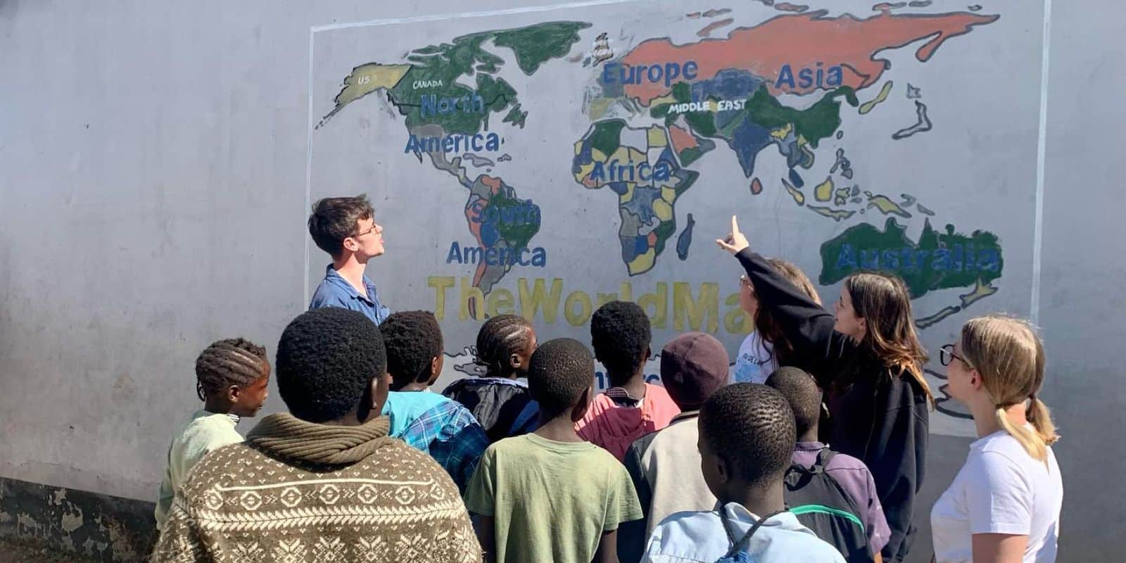 a foreign woman pointing to a map painted in a wall surrounded by other foreign and local people