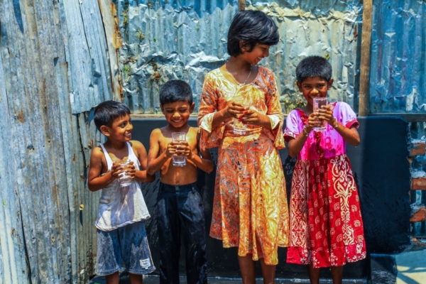 Four Asian children with glass of water