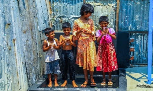 Four Asian children with glass of water