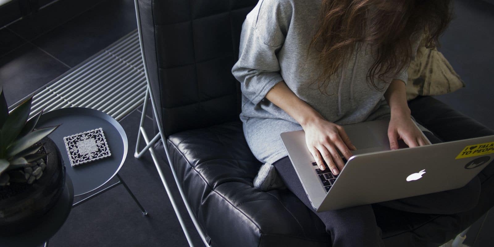 a woman sitting on a black leather chair while using her laptop