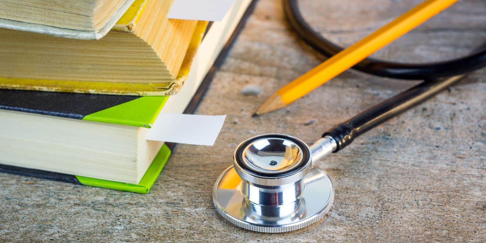 a book, stethoscope and pencil laid on top of the table