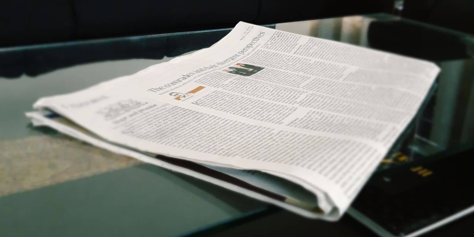 folded newspaper kept on a glass tabletop