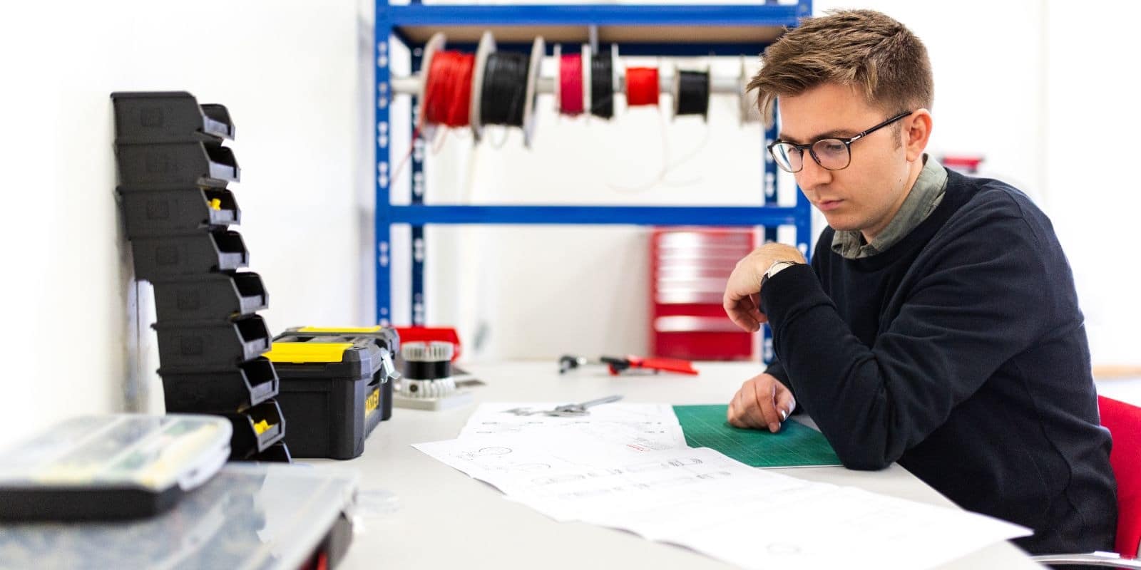 an engineer sitting while reading papers on his desk