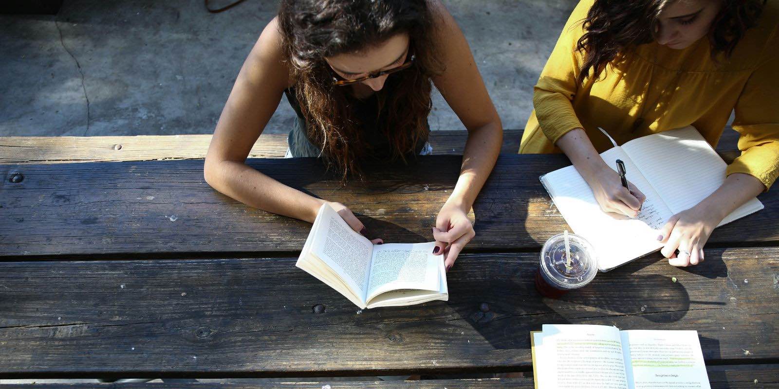 students sitting on a bench while reading a book
