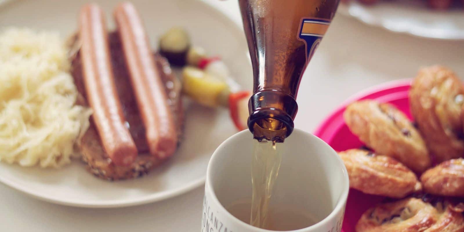 a german beer poured in a cup with german food on top of a table