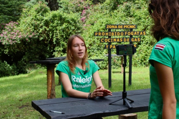 Girl behind table doing interview outdoor