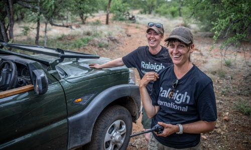 two Raleigh volunteers outside near a green vehicle