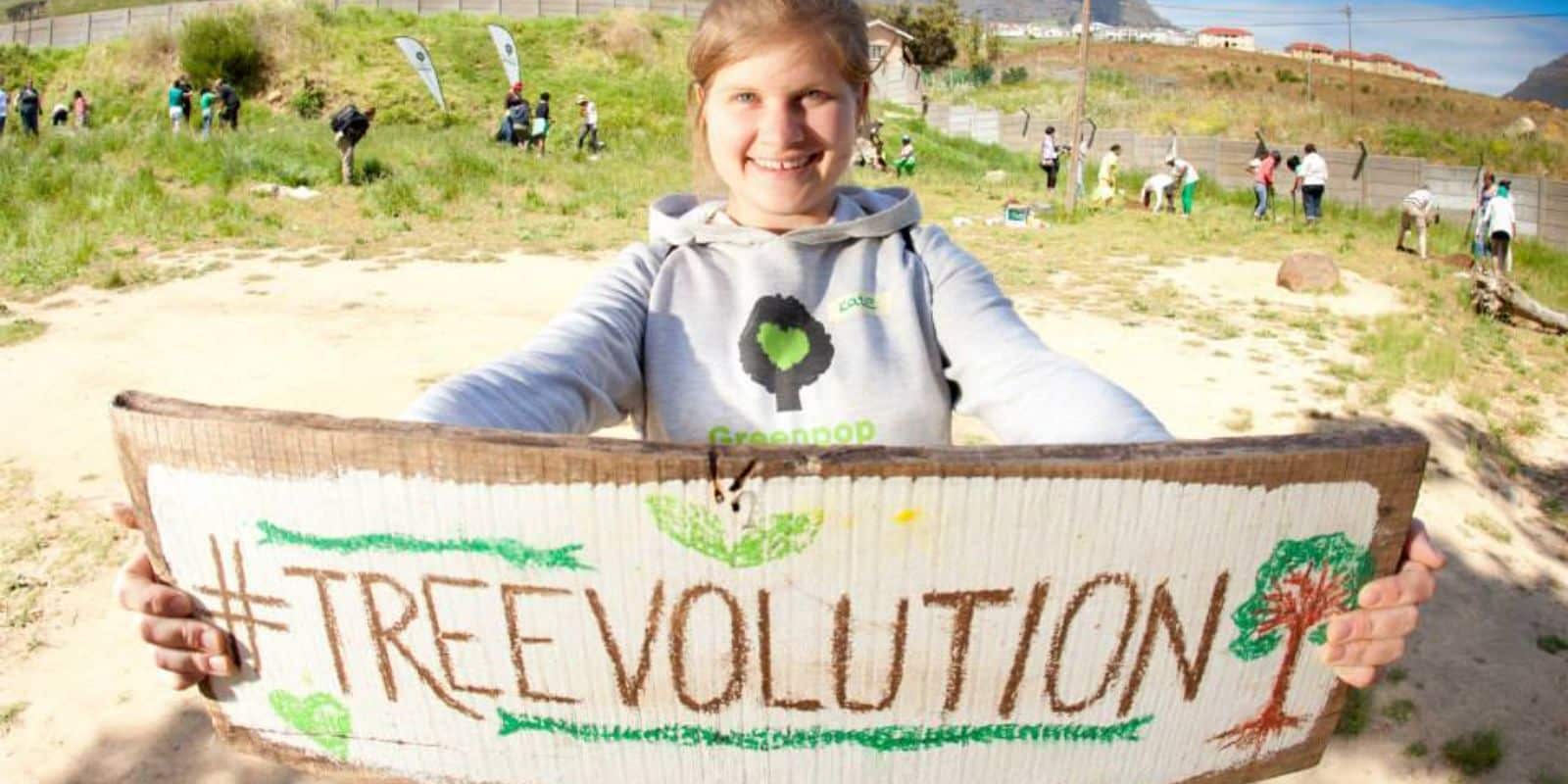 Volunteer on a sustainable project holds up a green-positive poster