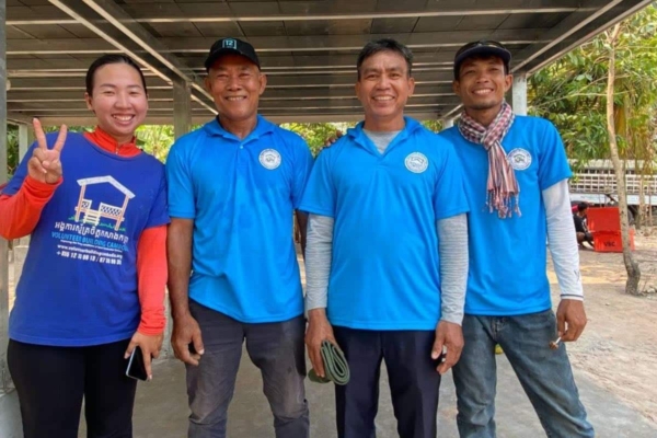 volunteers wearing blue shirts posing under a building structure