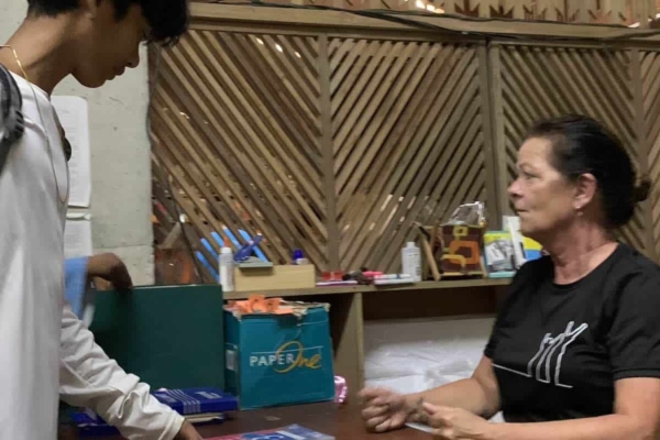 a volunteer looking at her computer while talking to a boy