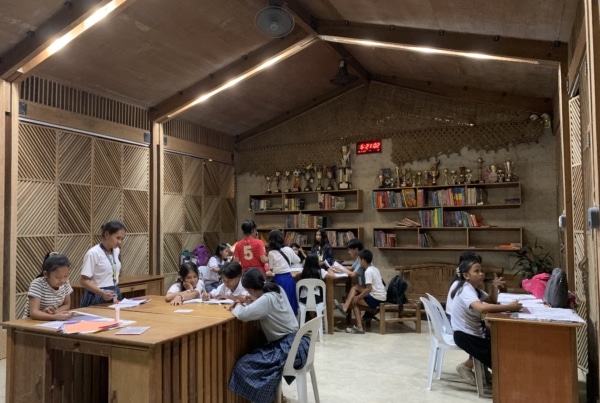 students working in a wooden library with bookshelves and trophies