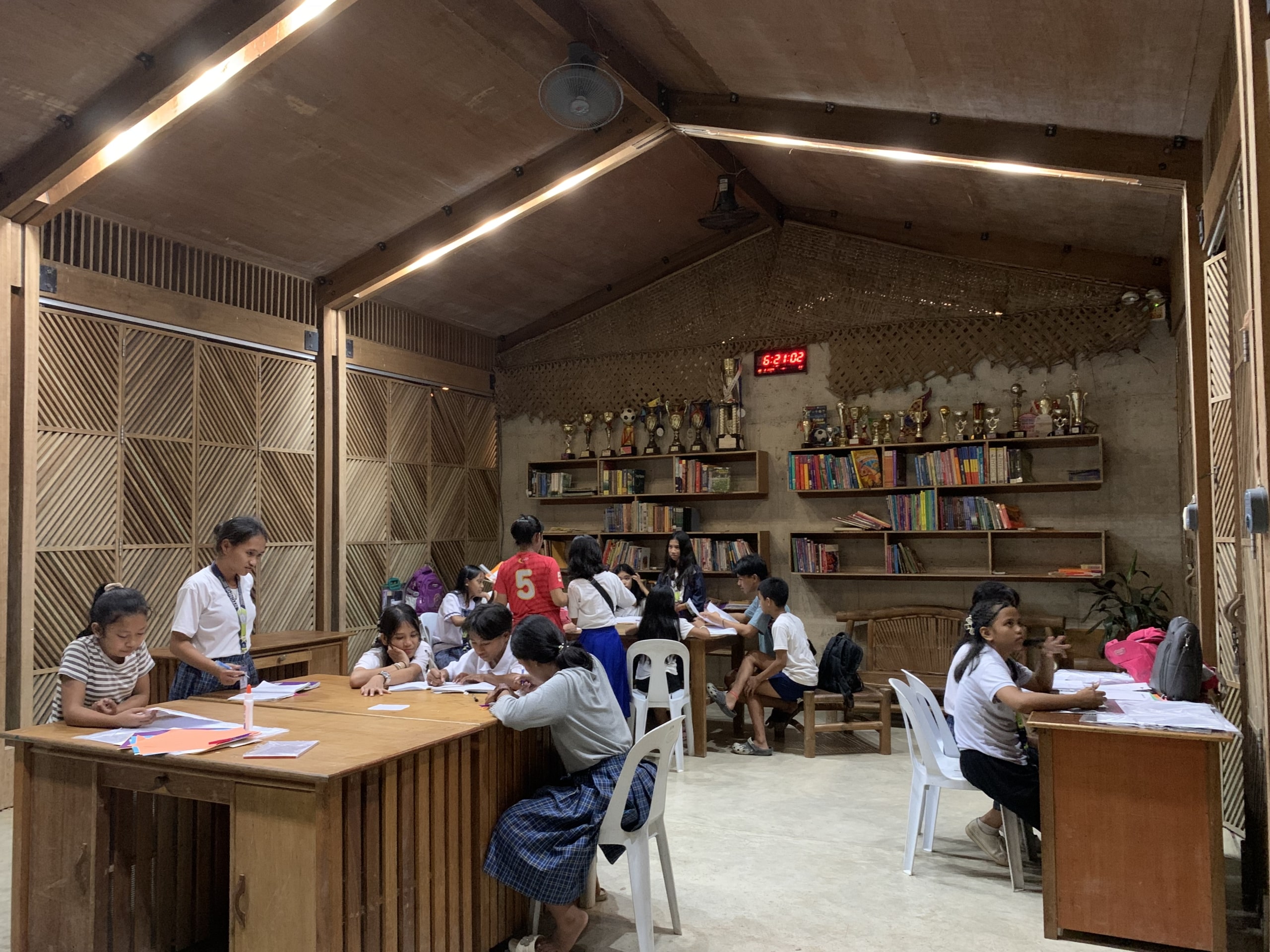 students working in a wooden library with bookshelves and trophies