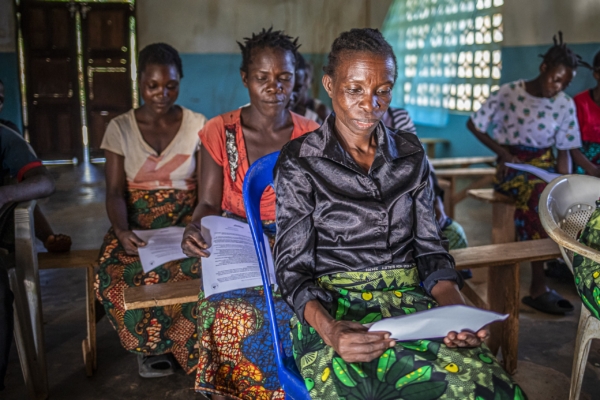 Women in Malawi sitting in a classroom, participating in an agroforestry internship session, reading educational materials related to sustainable farming.
