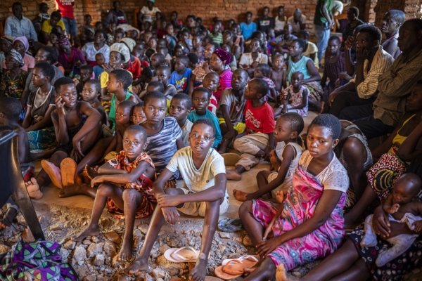A large group of children and adults sitting attentively on the floor during an agroforestry workshop in Malawi, eager to learn about sustainable agriculture.