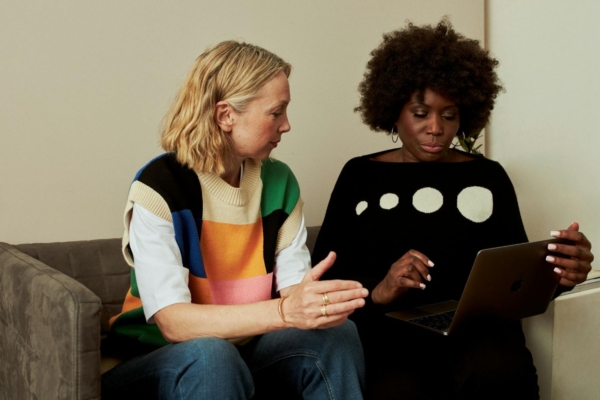 Two interns in Europe collaborate on a laptop during their communications internship in a casual office setting.